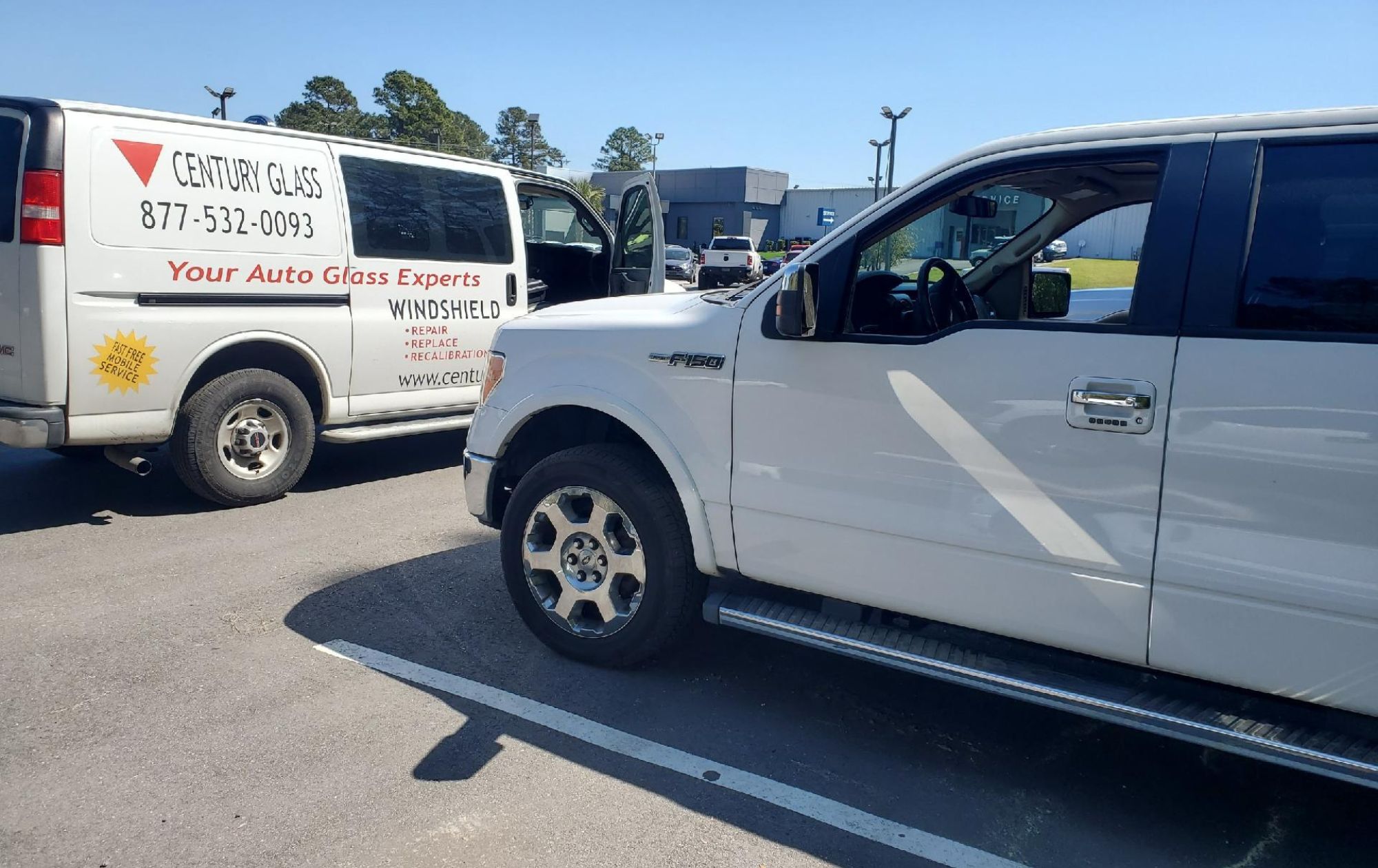 Windshield on stand next to a navy blue Mustang outside home.