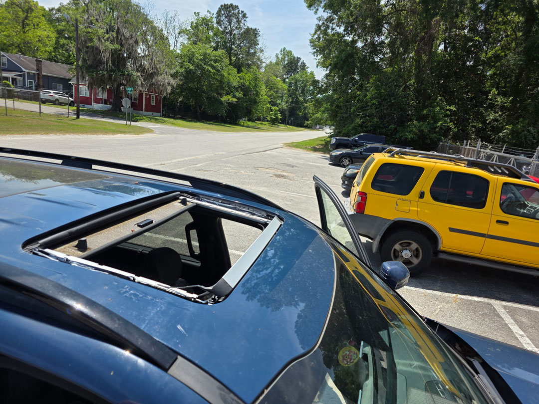 duct taped sunroof on dirty red car.